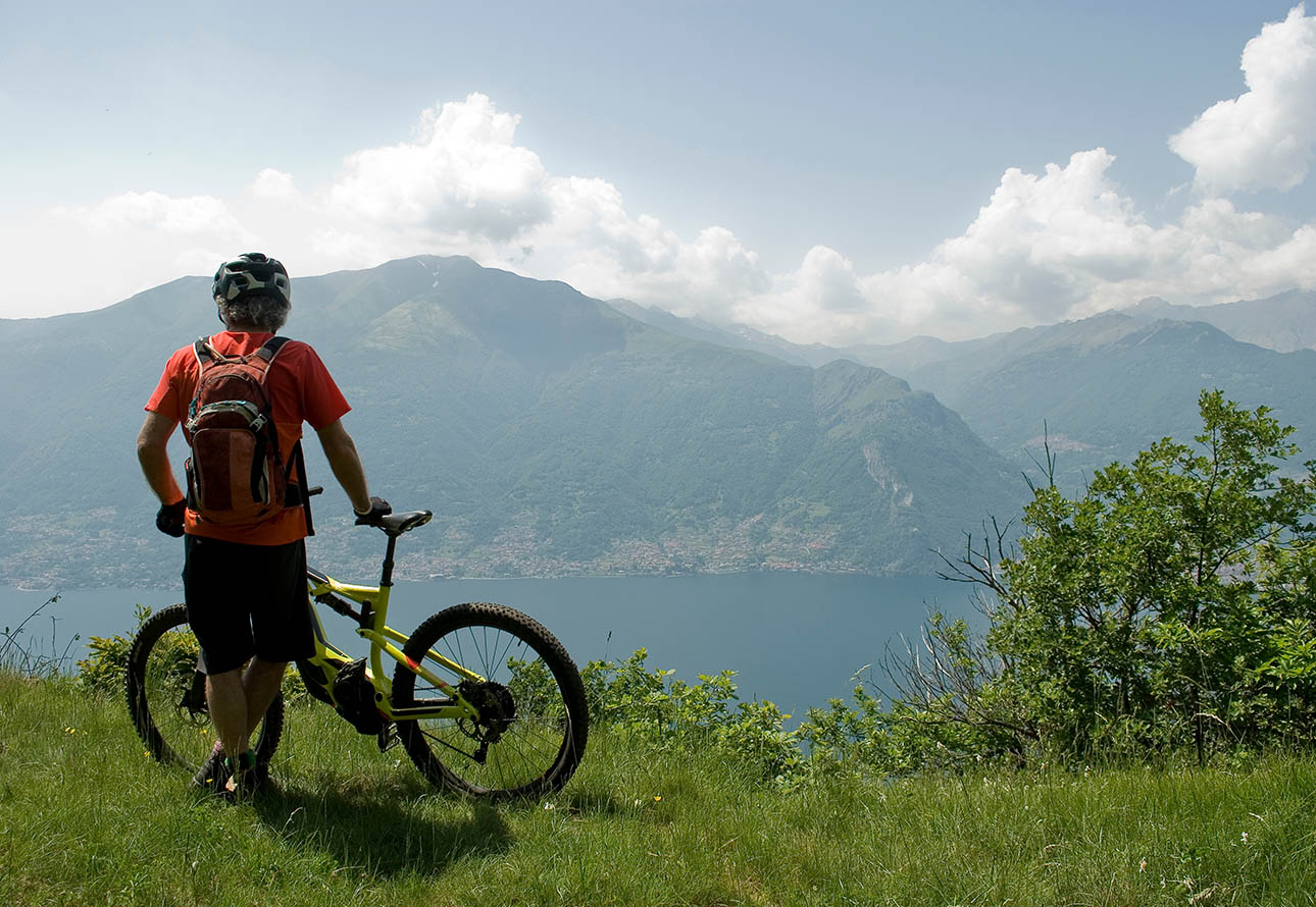 Motociclista disfrutando de la vista panorámica del lago Como en medio de montañas
