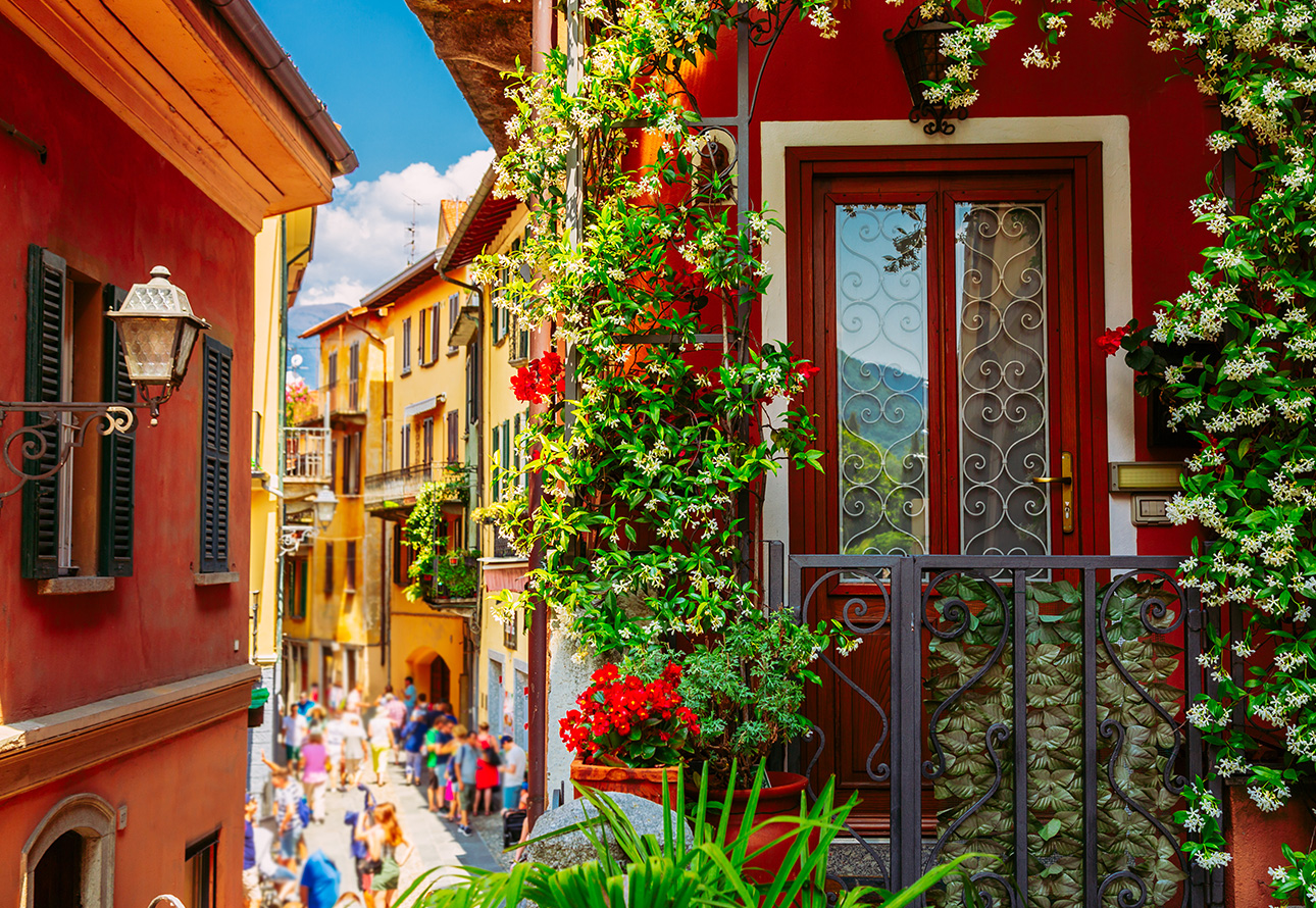The picture showcases a busy street in Bellagio, with a lot of people walking down the narrow path and vibrant colors adding to the lively atmosphere