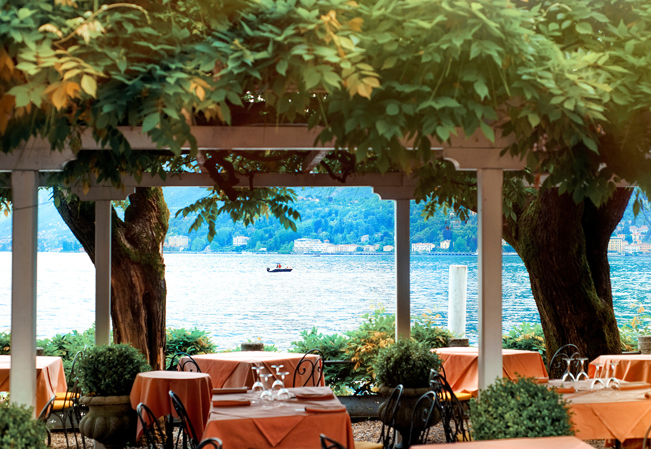 Scenic patio with tables and chairs, providing a delightful lunch setting under umbrellas at Bellagio with a beautiful lake view.