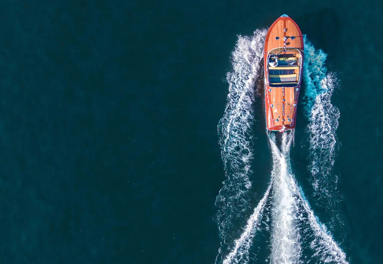  the image of a speed boat viewed from the top, traveling through the water with a wake