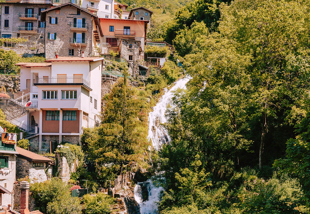 Eine kleine Stadt inmitten malerischer Häuser wird von den faszinierenden Wasserfällen von Nesso geschmückt
