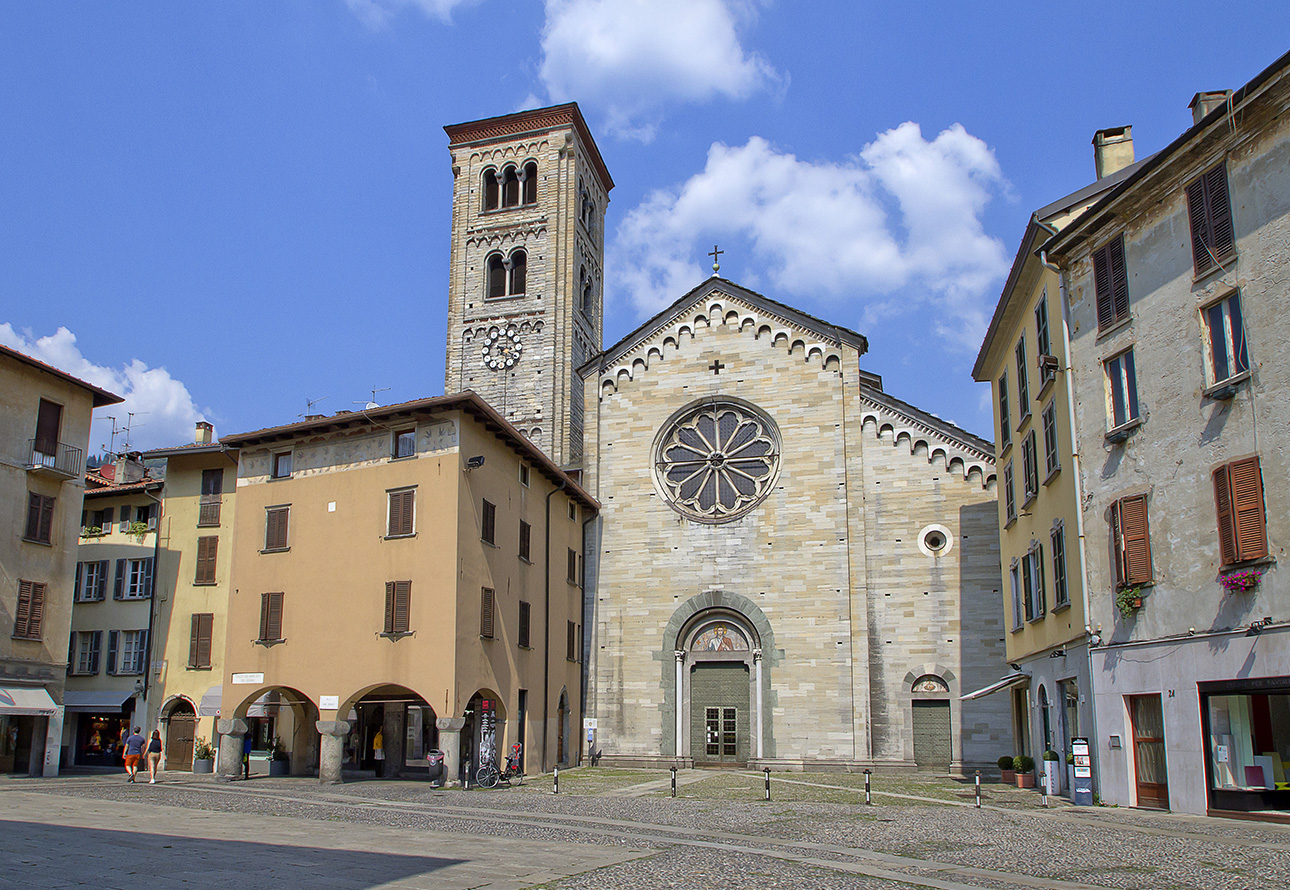 La Basílica de San Fedele Como, una iglesia con una torre de reloj, se alza en el centro de una ciudad.