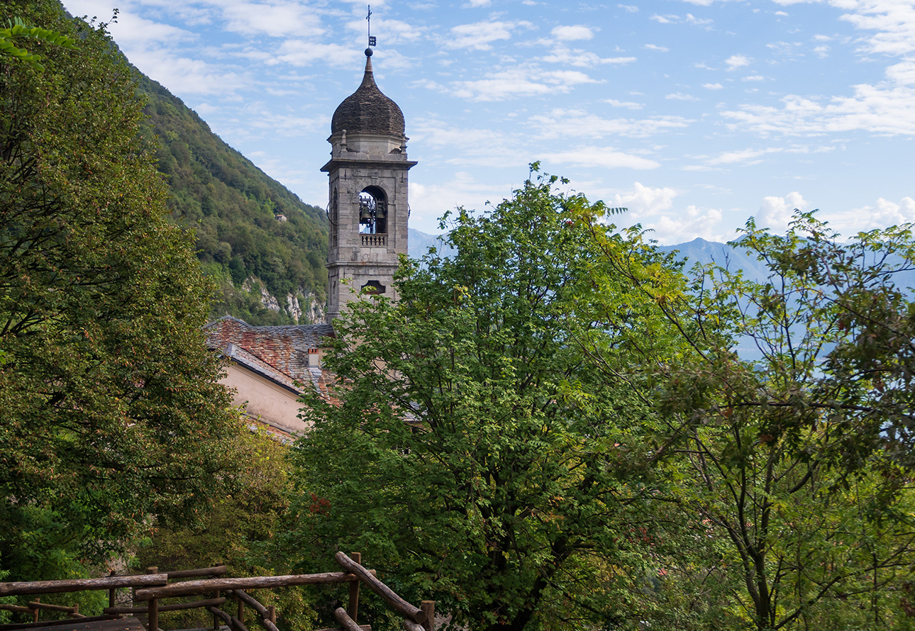 Un pintoresco puente de madera que cruza un río en el Sacro Monte di Ossuccio, con un sereno telón de fondo natural.