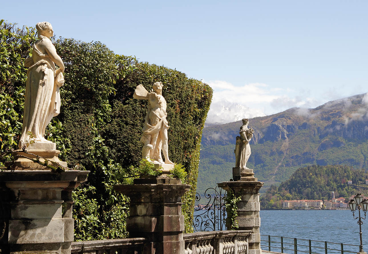 In einer Reihe stehende Skulpturen repräsentieren die Schönheit der Kunst und Kultur der Villa Carlotta mit Blick auf den Comer See