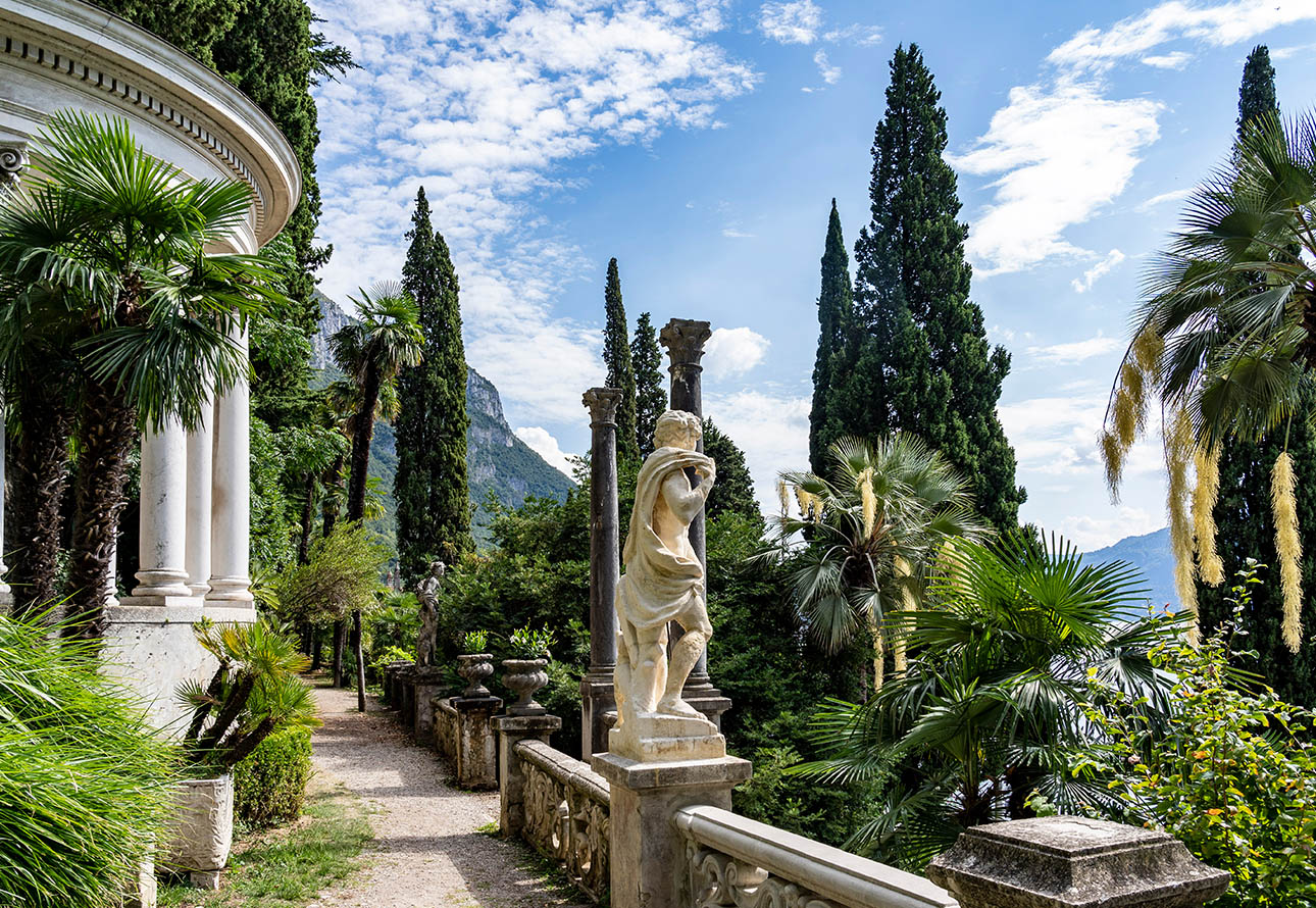 Ein formeller Garten, geschmückt mit eleganten Statuen und üppigen Bäumen, der eine ruhige und malerische Szene schafft.