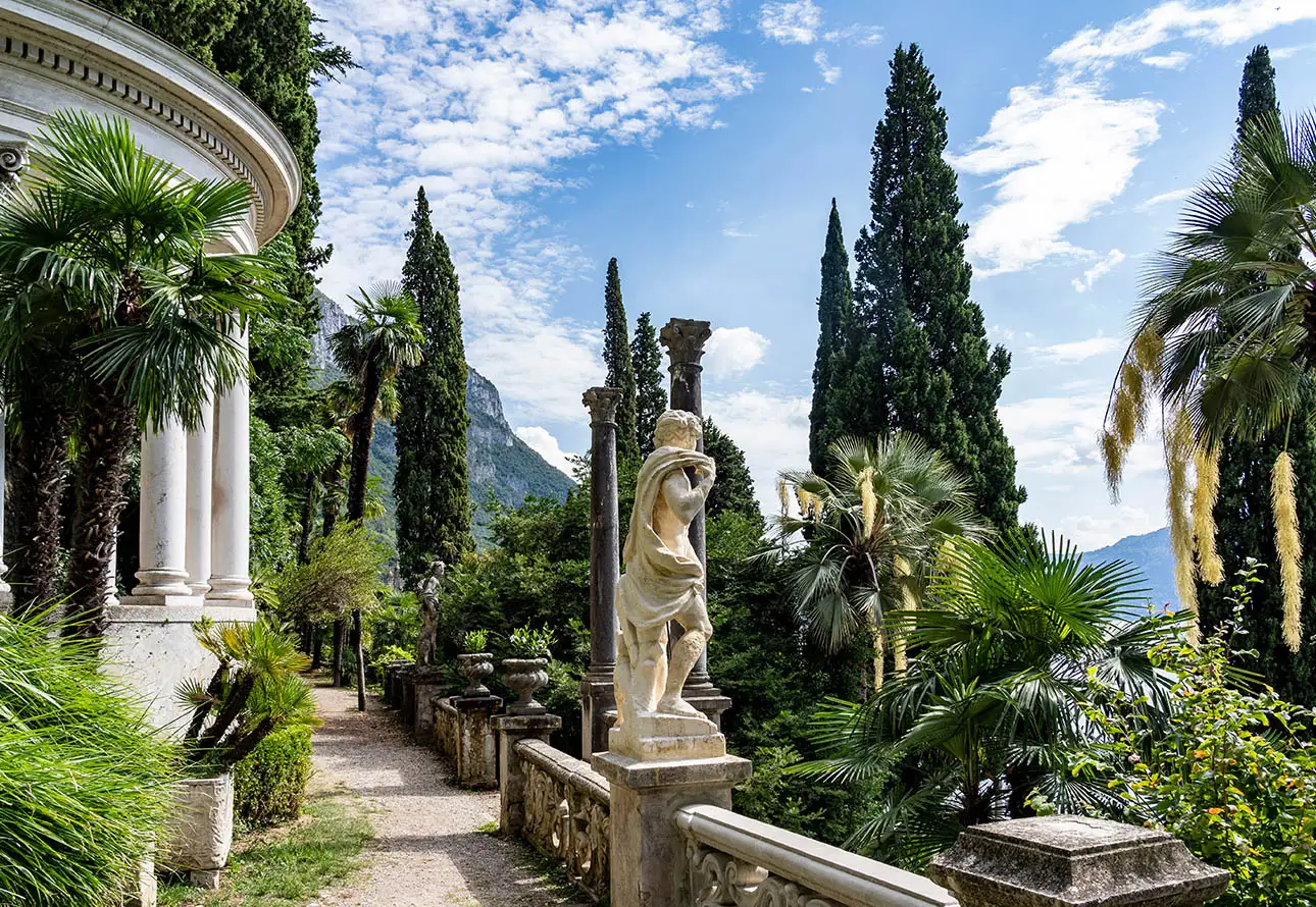 A formal garden adorned with elegant statues and lush trees, creating a serene and picturesque scene.