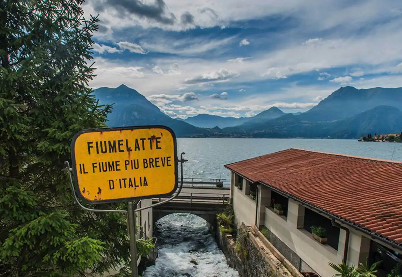 'Italian sign for filatelte near Fiumelatte river with red rooftop in view