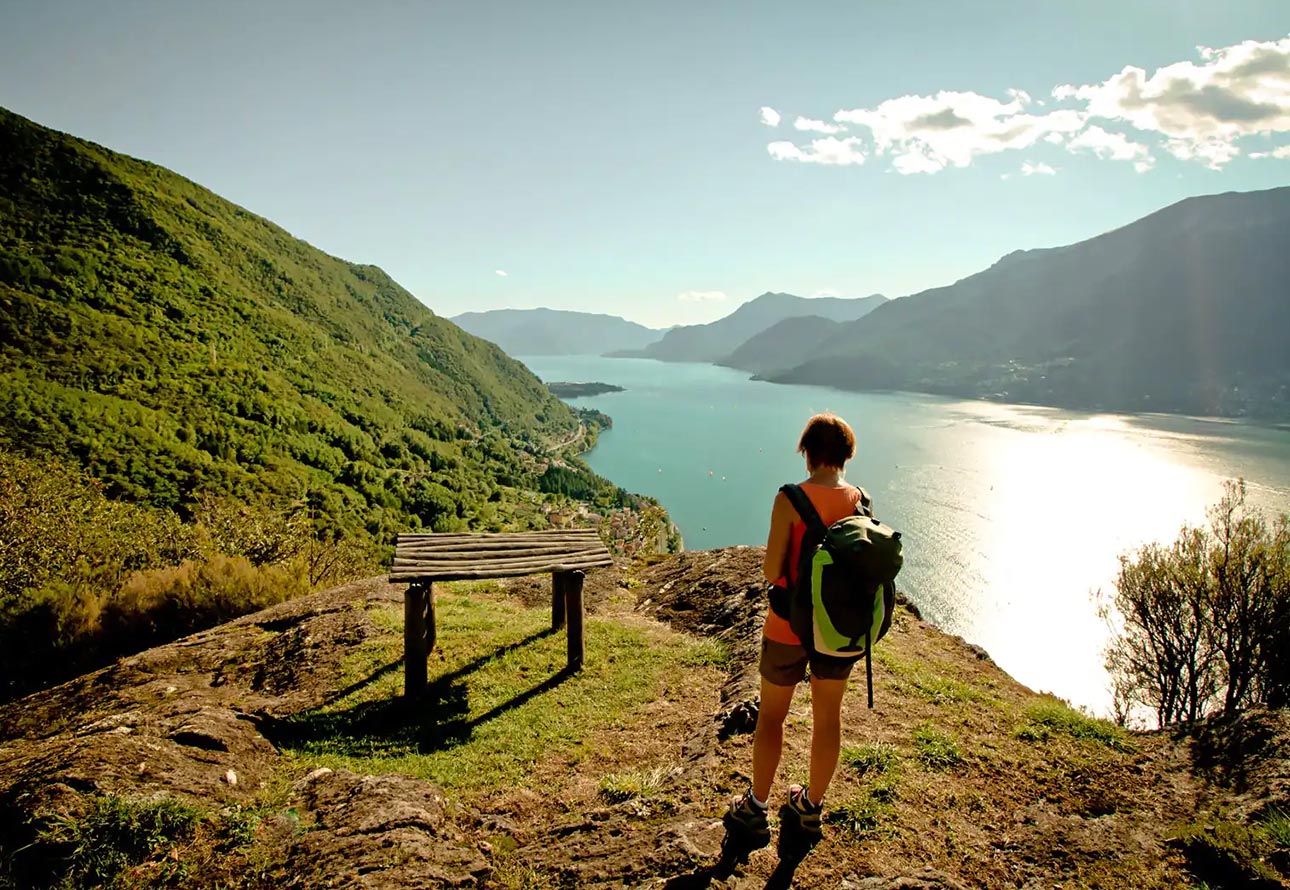 Eine Person mit Rucksack steht auf einem Sentiero del Viandante, einem berühmten Wanderweg, und bietet einen atemberaubenden Blick auf den Comer See