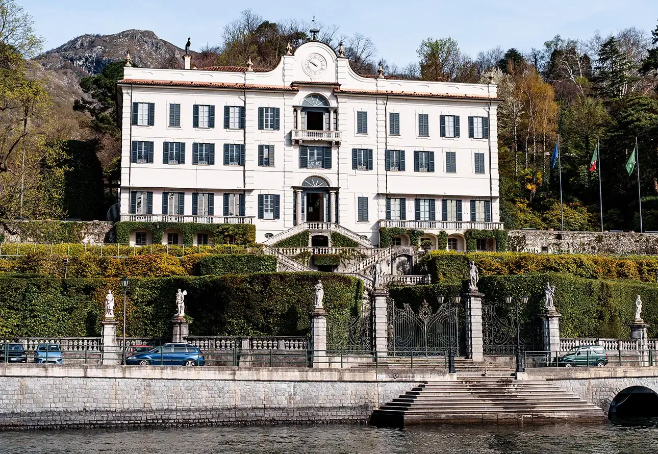 A large white building with a fountain in front of it, showcasing Villa Carlotta view from the lake